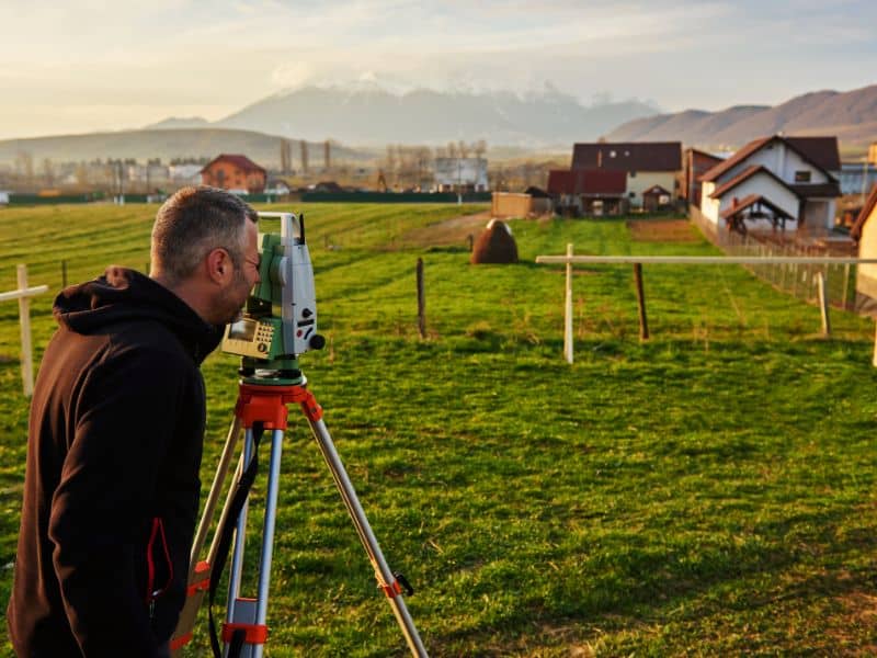 Land surveyor measuring residential property lines for a boundary survey cost estimate